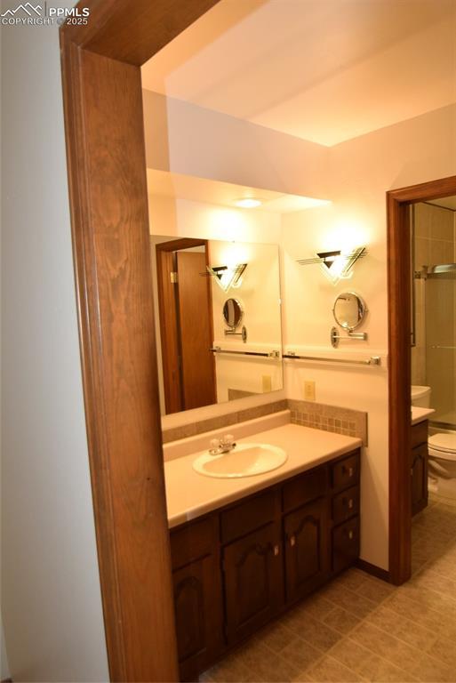 bathroom featuring vanity, toilet, a shower, and tile patterned flooring