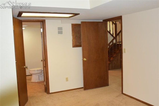 empty room with light colored carpet, stairway, and baseboards