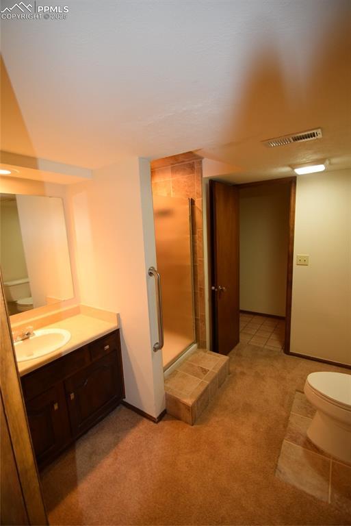 full bath featuring toilet, a stall shower, vanity, and baseboards