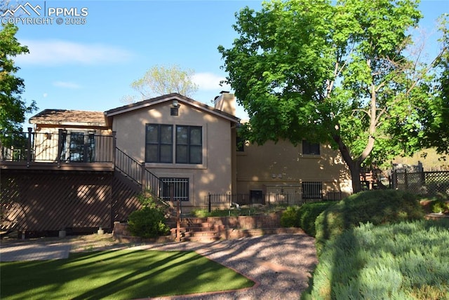 back of house with stairs, stucco siding, a chimney, and a deck