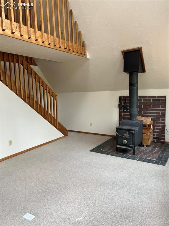 646 Grey Eagle Dr, Cripple Creek, CO 80813 - unfurnished living room with carpet, a wood stove, and baseboards