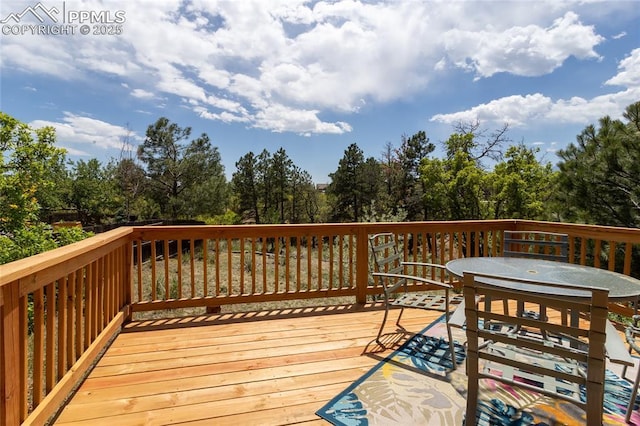 6331 Mesedge Dr, Colorado Springs, CO 80919 - wooden deck with outdoor dining area and view of wooded area