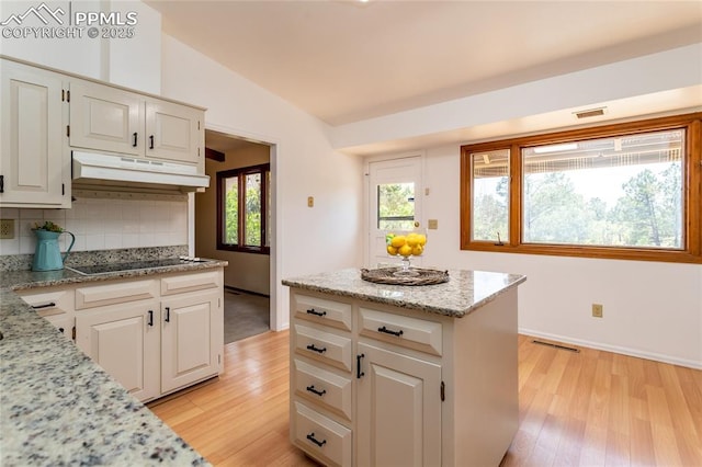 6331 Mesedge Dr, Colorado Springs, CO 80919 - kitchen with black electric cooktop, light wood-style flooring, backsplash, plenty of natural light, and vaulted ceiling