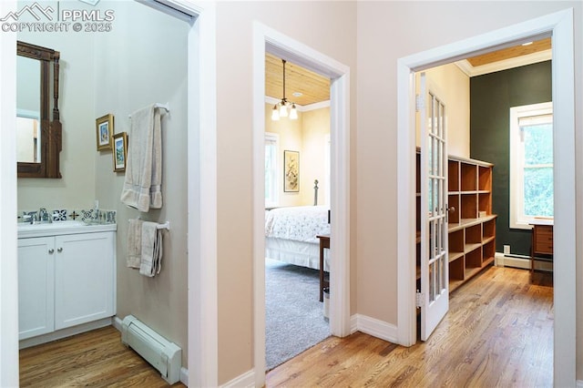 15 Cypress Ln, Colorado Springs, CO 80906 - hallway with baseboard heating, wood finished floors, crown molding, a sink, and a chandelier
