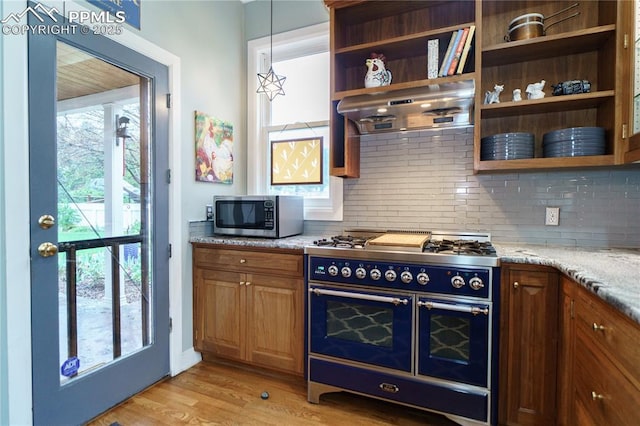 15 Cypress Ln, Colorado Springs, CO 80906 - kitchen with double oven range, stainless steel microwave, ventilation hood, decorative backsplash, and light stone counters