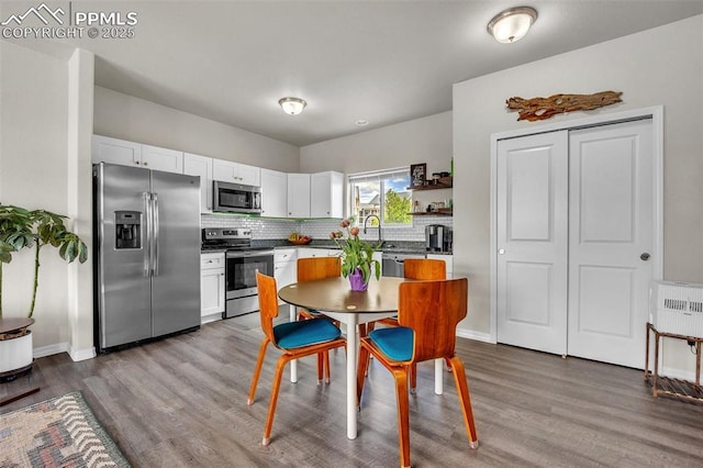 793 Grissom Dr, Colorado Springs, CO 80915 - kitchen with stainless steel appliances, wood finished floors, white cabinets, decorative backsplash, and baseboards