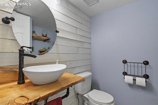 7534 Sistine Ln, Fountain, CO 80817 - bathroom with wood walls, a sink, toilet, and a textured ceiling