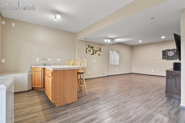 7534 Sistine Ln, Fountain, CO 80817 - kitchen featuring a breakfast bar area, wood finished floors, open floor plan, a peninsula, and recessed lighting