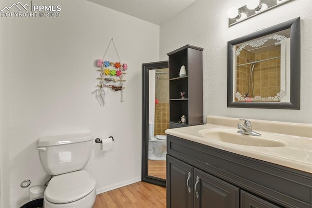 7534 Sistine Ln, Fountain, CO 80817 - bathroom with toilet, wood finished floors, vanity, a tile shower, and baseboards