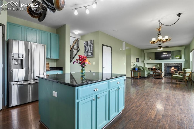 7534 Sistine Ln, Fountain, CO 80817 - kitchen featuring stainless steel fridge, a tiled fireplace, a chandelier, open floor plan, and a kitchen island
