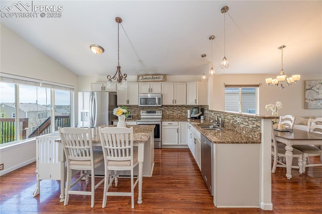6463 Binder Dr, Colorado Springs, CO 80923 - kitchen with appliances with stainless steel finishes, a chandelier, backsplash, a breakfast bar area, and a sink