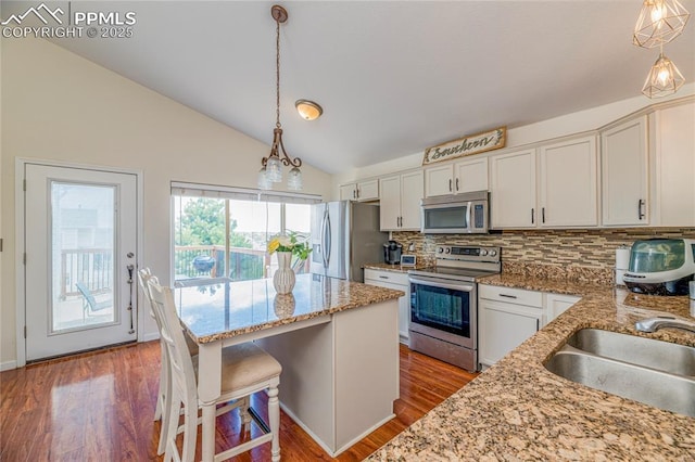6463 Binder Dr, Colorado Springs, CO 80923 - kitchen featuring appliances with stainless steel finishes, a sink, backsplash, vaulted ceiling, and wood finished floors