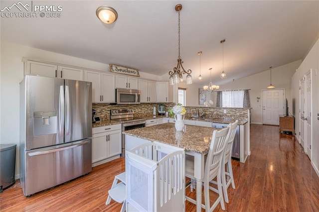6463 Binder Dr, Colorado Springs, CO 80923 - kitchen with appliances with stainless steel finishes, tasteful backsplash, a chandelier, a peninsula, and vaulted ceiling