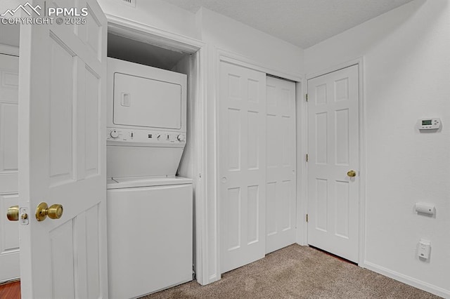3300 W Florida Ave Unit 26, Denver, CO 80219 - laundry room with estacked washer and dryer, carpet flooring, and baseboards