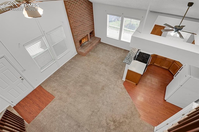 3300 W Florida Ave Unit 26, Denver, CO 80219 - living room featuring ceiling fan, a fireplace, light wood-style floors, a textured ceiling, and light carpet