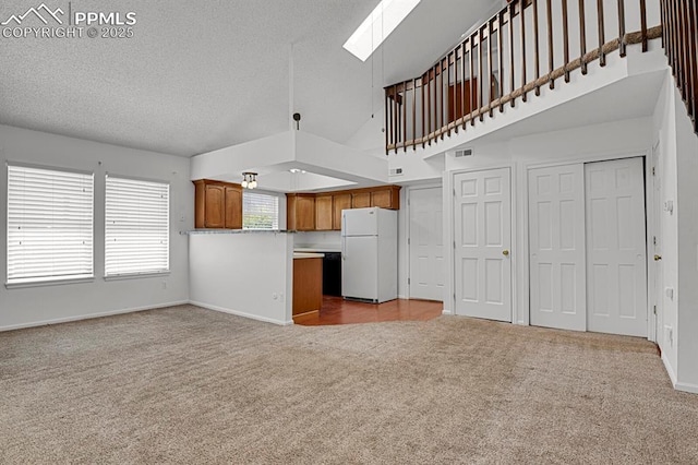 3300 W Florida Ave Unit 26, Denver, CO 80219 - unfurnished living room featuring carpet, a skylight, baseboards, a textured ceiling, and a towering ceiling