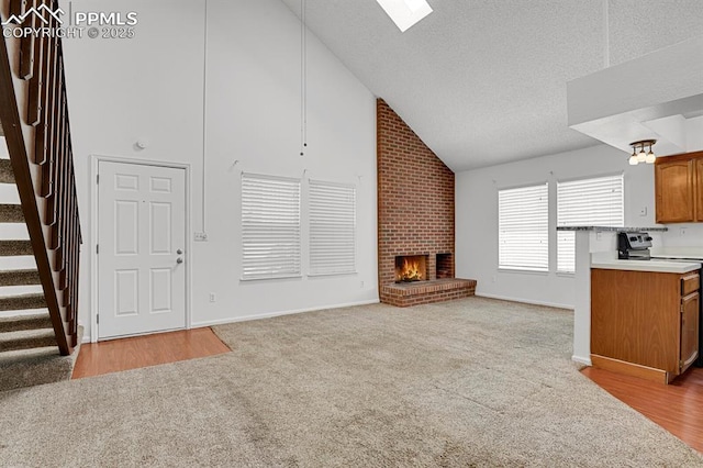 3300 W Florida Ave Unit 26, Denver, CO 80219 - unfurnished living room featuring stairs, high vaulted ceiling, a brick fireplace, light carpet, and baseboards