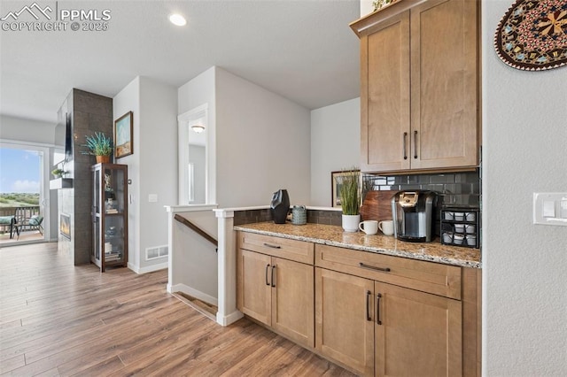 2267 Merlot Dr, Colorado Springs, CO 80921 - kitchen featuring light wood-type flooring, a peninsula, light stone countertops, decorative backsplash, and baseboards