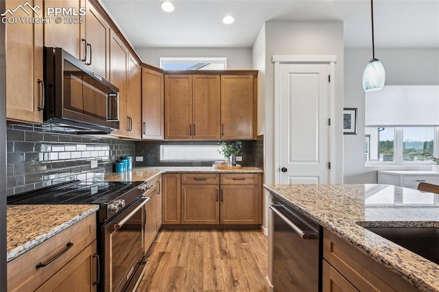 2267 Merlot Dr, Colorado Springs, CO 80921 - kitchen featuring appliances with stainless steel finishes, light wood-style flooring, backsplash, light stone counters, and recessed lighting