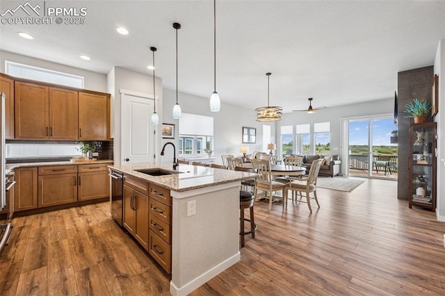 2267 Merlot Dr, Colorado Springs, CO 80921 - kitchen with a sink, brown cabinetry, open floor plan, wood finished floors, and a kitchen island with sink