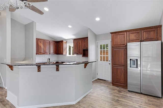 4465 Archwood Dr, Colorado Springs, CO 80920 - kitchen featuring stainless steel fridge, a breakfast bar area, lofted ceiling, tasteful backsplash, and dark stone counters