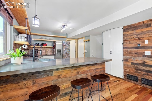 2620 Warrenton Way, Colorado Springs, CO 80922 - kitchen featuring stainless steel refrigerator with ice dispenser, light wood-style flooring, open shelves, white cabinets, and wooden walls