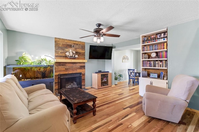 2620 Warrenton Way, Colorado Springs, CO 80922 - living area with a ceiling fan, light wood-type flooring, a textured ceiling, a large fireplace, and wooden walls