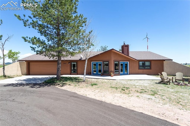 7815 Mallard Dr, Peyton, CO 80831 - view of front of property featuring french doors, a chimney, a garage, concrete driveway, and a fire pit