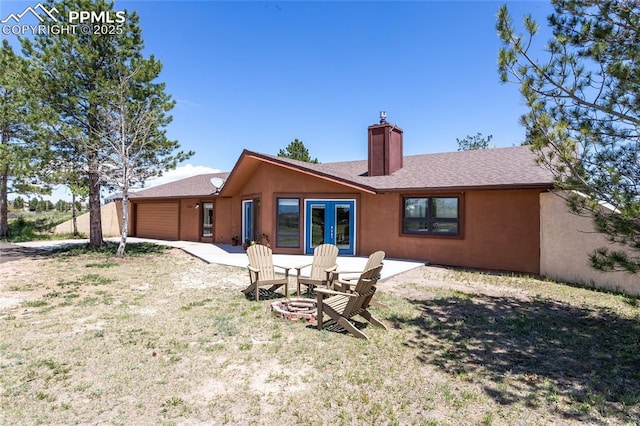 7815 Mallard Dr, Peyton, CO 80831 - back of house featuring an attached garage, a chimney, a yard, and stucco siding