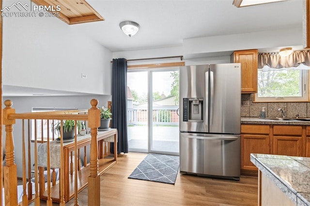 7350 Devinney Ct, Arvada, CO 80005 - kitchen featuring stainless steel fridge, a sink, tile counters, light wood finished floors, and tasteful backsplash