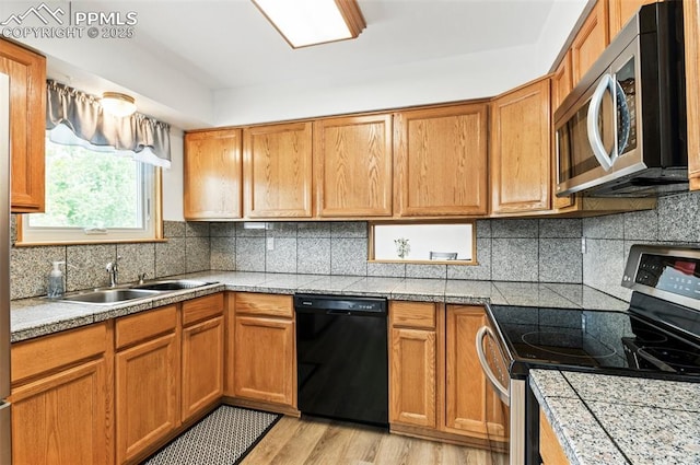 7350 Devinney Ct, Arvada, CO 80005 - kitchen with appliances with stainless steel finishes, a sink, tasteful backsplash, light wood-type flooring, and brown cabinets