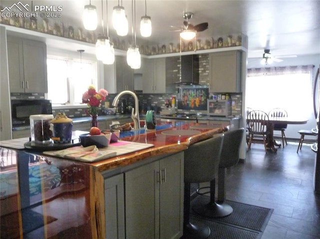 4307 Valli Vista Rd, Colorado Springs, CO 80915 - kitchen featuring a ceiling fan, gray cabinetry, backsplash, a center island with sink, and black microwave