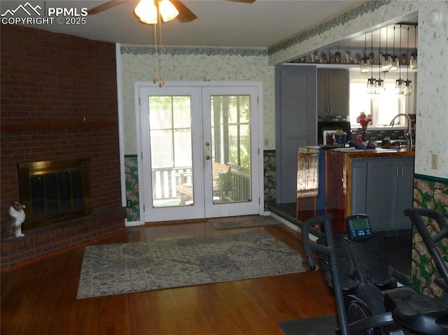 4307 Valli Vista Rd, Colorado Springs, CO 80915 - living room with wallpapered walls, french doors, wood finished floors, a ceiling fan, and a brick fireplace