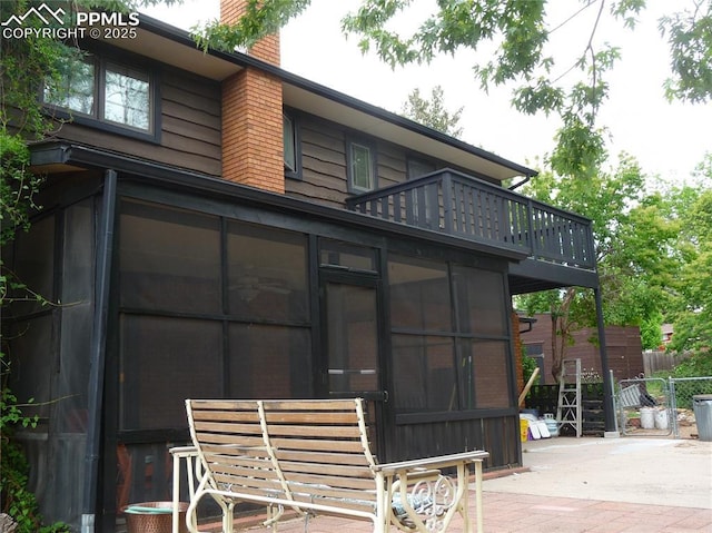 4307 Valli Vista Rd, Colorado Springs, CO 80915 - rear view of property with a sunroom, a patio area, a chimney, and a balcony