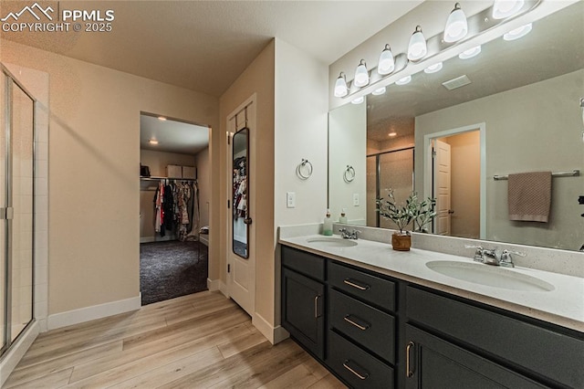 12670 Granite Ridge Dr, Peyton, CO 80831 - full bath with a walk in closet, wood finished floors, a stall shower, double vanity, and baseboards