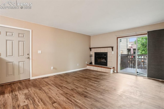 27 Stovel Cir, Colorado Springs, CO 80916 - unfurnished living room featuring wood finished floors, baseboards, and a tiled fireplace