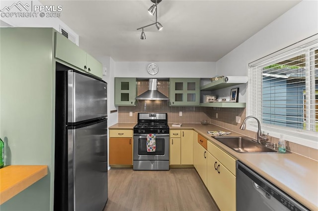 2321 N Meade Ave, Colorado Springs, CO 80907 - kitchen with appliances with stainless steel finishes, wall chimney range hood, a sink, light wood-style flooring, and tasteful backsplash