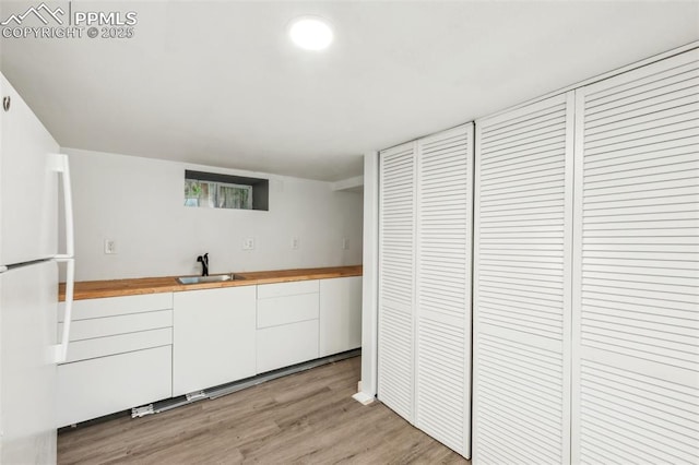 817 W Kiowa St, Colorado Springs, CO 80905 - kitchen featuring freestanding refrigerator, butcher block countertops, a sink, white cabinetry, and light wood-style floors