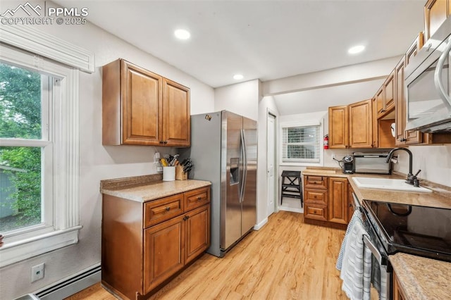 817 W Kiowa St, Colorado Springs, CO 80905 - kitchen featuring stainless steel appliances, a sink, light wood-type flooring, baseboard heating, and brown cabinets