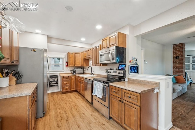 817 W Kiowa St, Colorado Springs, CO 80905 - kitchen featuring appliances with stainless steel finishes, light wood finished floors, a sink, light countertops, and brown cabinetry