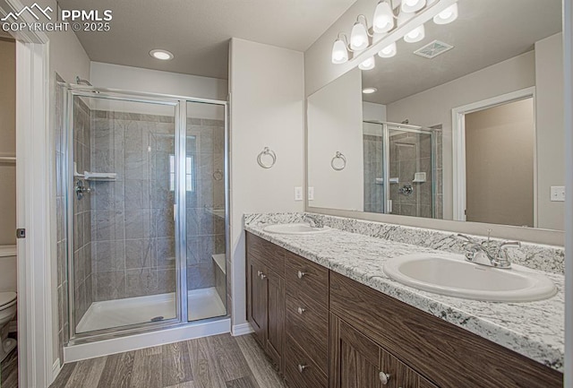 5216 Devers Ct, Colorado Springs, CO 80925 - bathroom with toilet, wood finished floors, a shower stall, double vanity, and recessed lighting