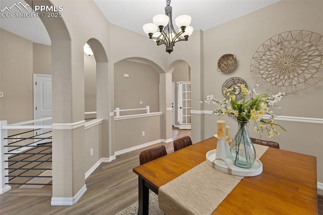 8059 Cinnamon Ct, Colorado Springs, CO 80927 - dining room with arched walkways, wood finished floors, a chandelier, and baseboards