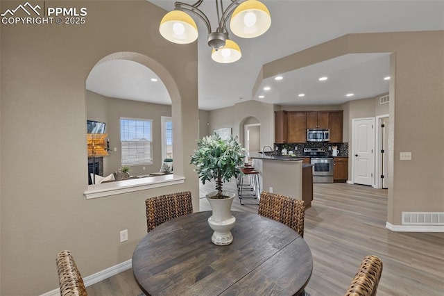 8059 Cinnamon Ct, Colorado Springs, CO 80927 - dining space with arched walkways, baseboards, light wood-type flooring, a chandelier, and recessed lighting