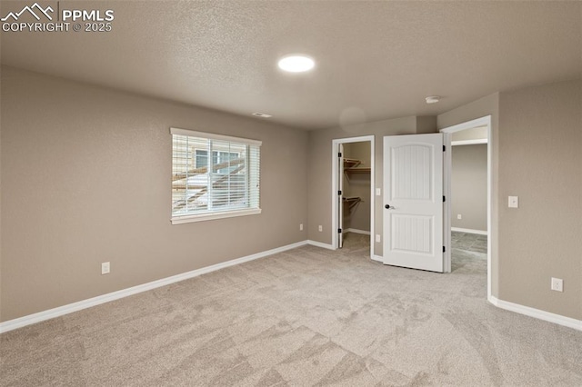 8059 Cinnamon Ct, Colorado Springs, CO 80927 - unfurnished bedroom with carpet floors, a textured ceiling, baseboards, and a walk in closet