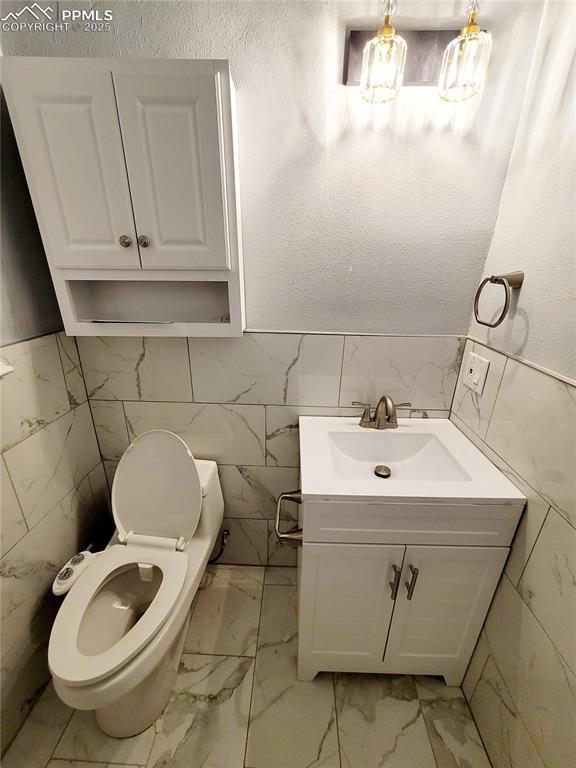 18 S 13th St, Colorado Springs, CO 80904 - bathroom featuring tile walls, vanity, marble finish floors, toilet, and wainscoting