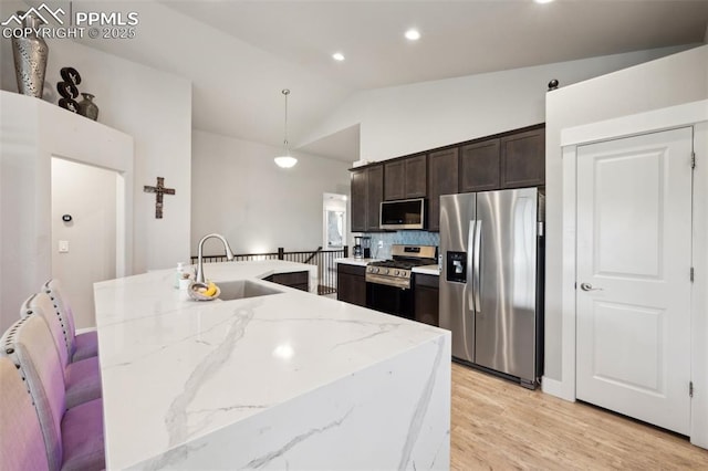 10442 Beckham St, Peyton, CO 80831 - kitchen featuring stainless steel appliances, a sink, lofted ceiling, dark brown cabinetry, and hanging light fixtures