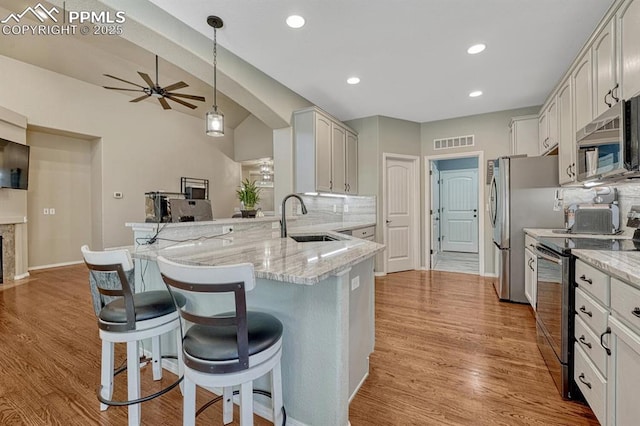 8055 Mount Hayden Dr, Colorado Springs, CO 80924 - kitchen with stainless steel appliances, ceiling fan, a breakfast bar area, a peninsula, and light stone counters