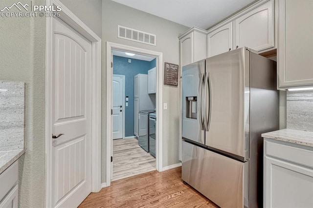 8055 Mount Hayden Dr, Colorado Springs, CO 80924 - kitchen featuring stainless steel fridge, light wood finished floors, light stone countertops, stove, and white cabinetry