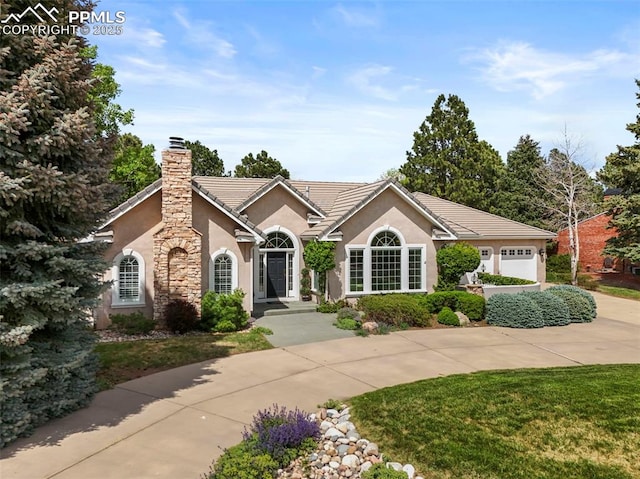 3479 Hill Cir, Colorado Springs, CO 80904 - single story home with stucco siding, a chimney, an attached garage, curved driveway, and a tile roof