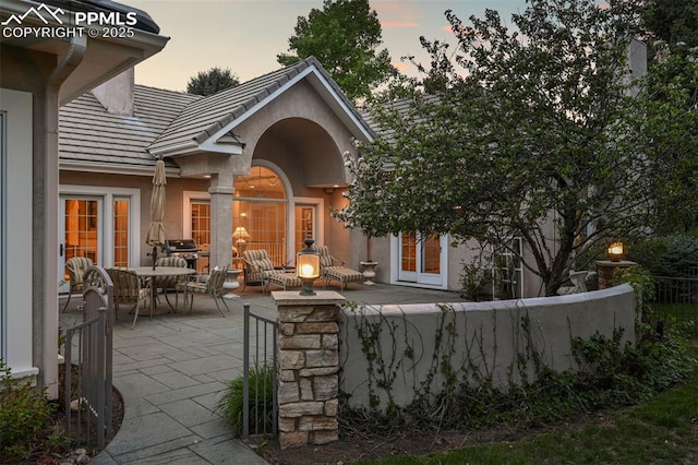 3479 Hill Cir, Colorado Springs, CO 80904 - back of property at dusk featuring a patio, stucco siding, a tiled roof, and outdoor dining space